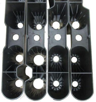 A black plastic divider with many holes for each row.